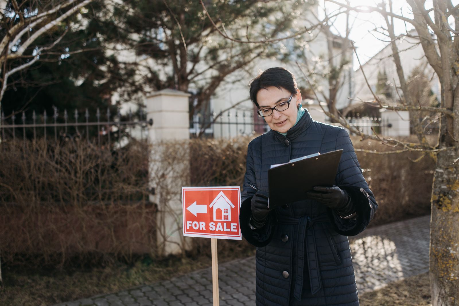 An appraiser inspecting the exterior of a house with a clipboard